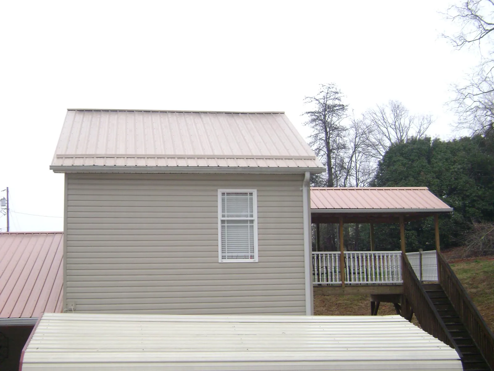 Tan metal roofs on a two story addition and attached porch, from a Roof Replacement job in Vashon