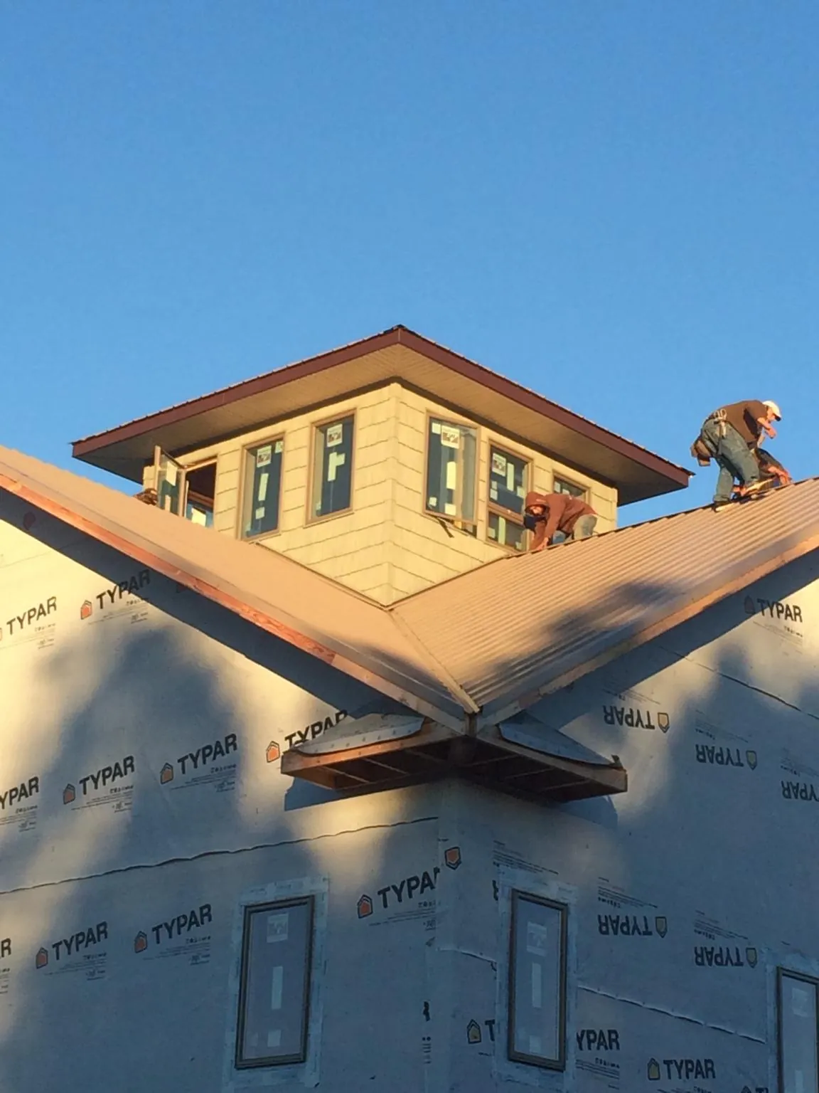 Roofers working around a rooftop cupola on a new metal roof at sunset — Roof Waterproofing in Vashon by Roofing Brothers